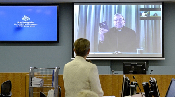 Cardinal George Pell appears before the Commission via videolink holding a bible