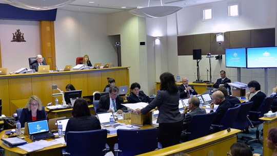 A crowded hearing room with Commissioners sitting in the distance in Darwin