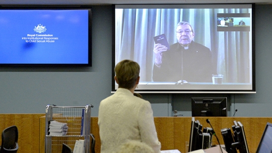 Cardinal George Pell appears before the Commission via videolink holding a bible
