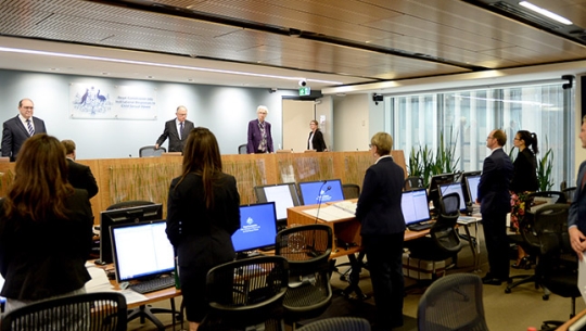Hearing room standing as Commissioners enter the room