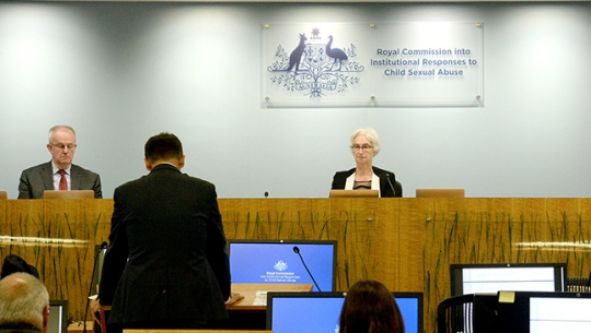 Counsel Assisting, David Lloyd addresses Commissioners with his back to the camera addresses from left to right: Commissioner Bob Atkinson AO APM and Justice Jennifer Coate