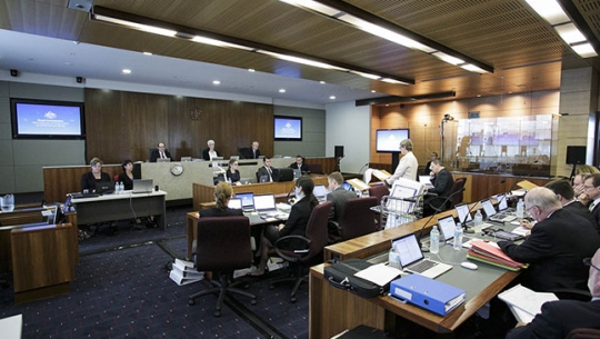 A hearing room with legal staff and commissioners sitting at a bench in the distance