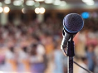 A microphone on a stand with a distant audience in the background